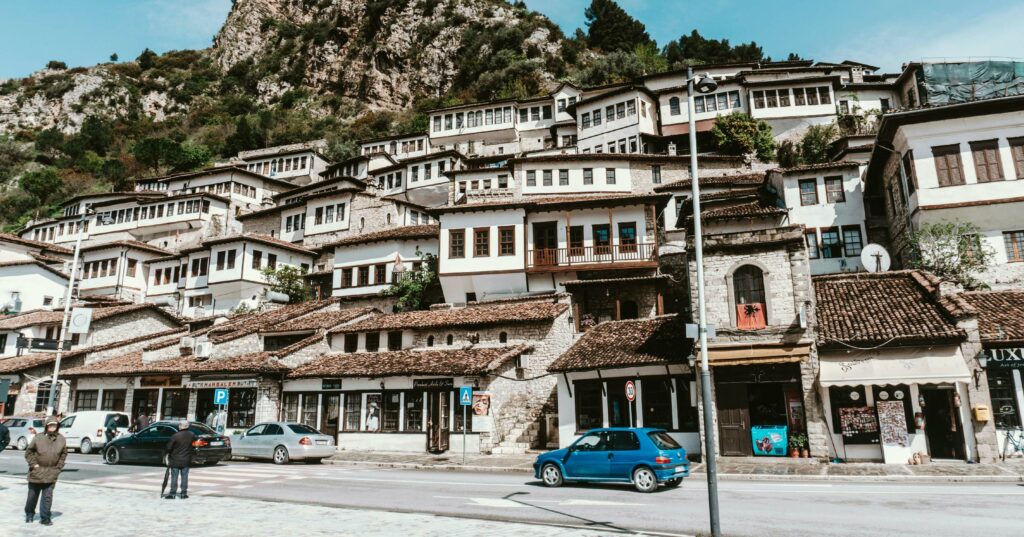 people walking on a street with several buildings on a steep in the background in places to visit in albania