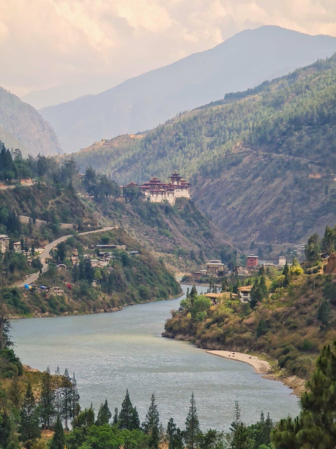 river flowing between two mountains with view of a Buddhist temple in the distance