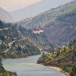 river flowing between two mountains with view of a Buddhist temple in the distance