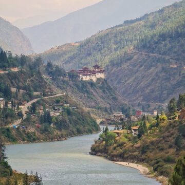 river flowing between two mountains with view of a Buddhist temple in the distance