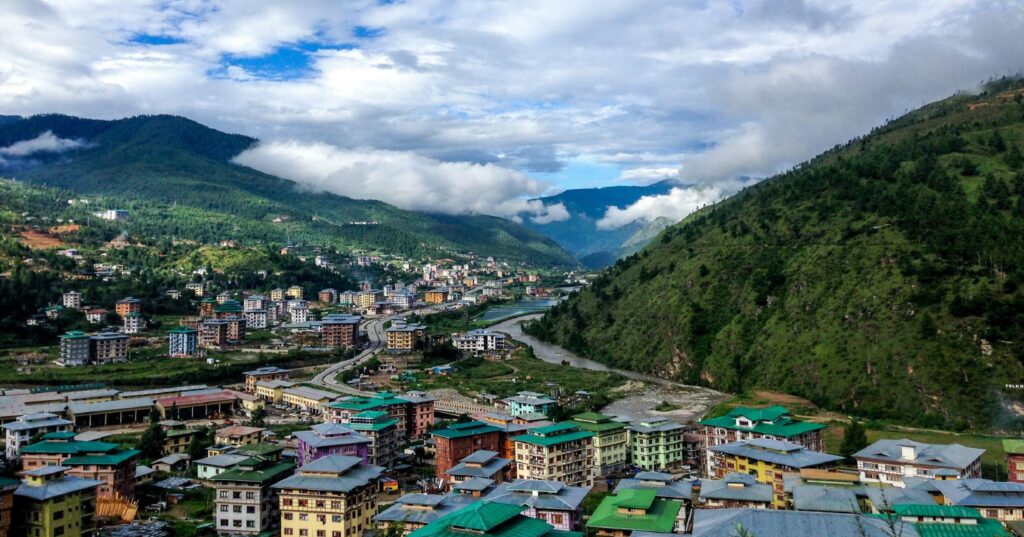 town packed with small houses in a valley with a hill in the background under blue sky