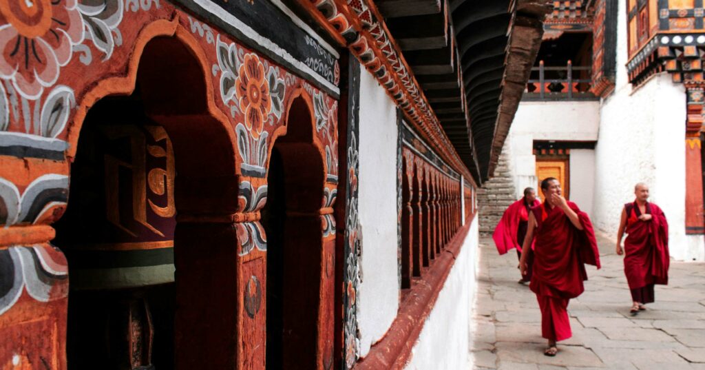 buddhist monks walking by the side of a wall with murals