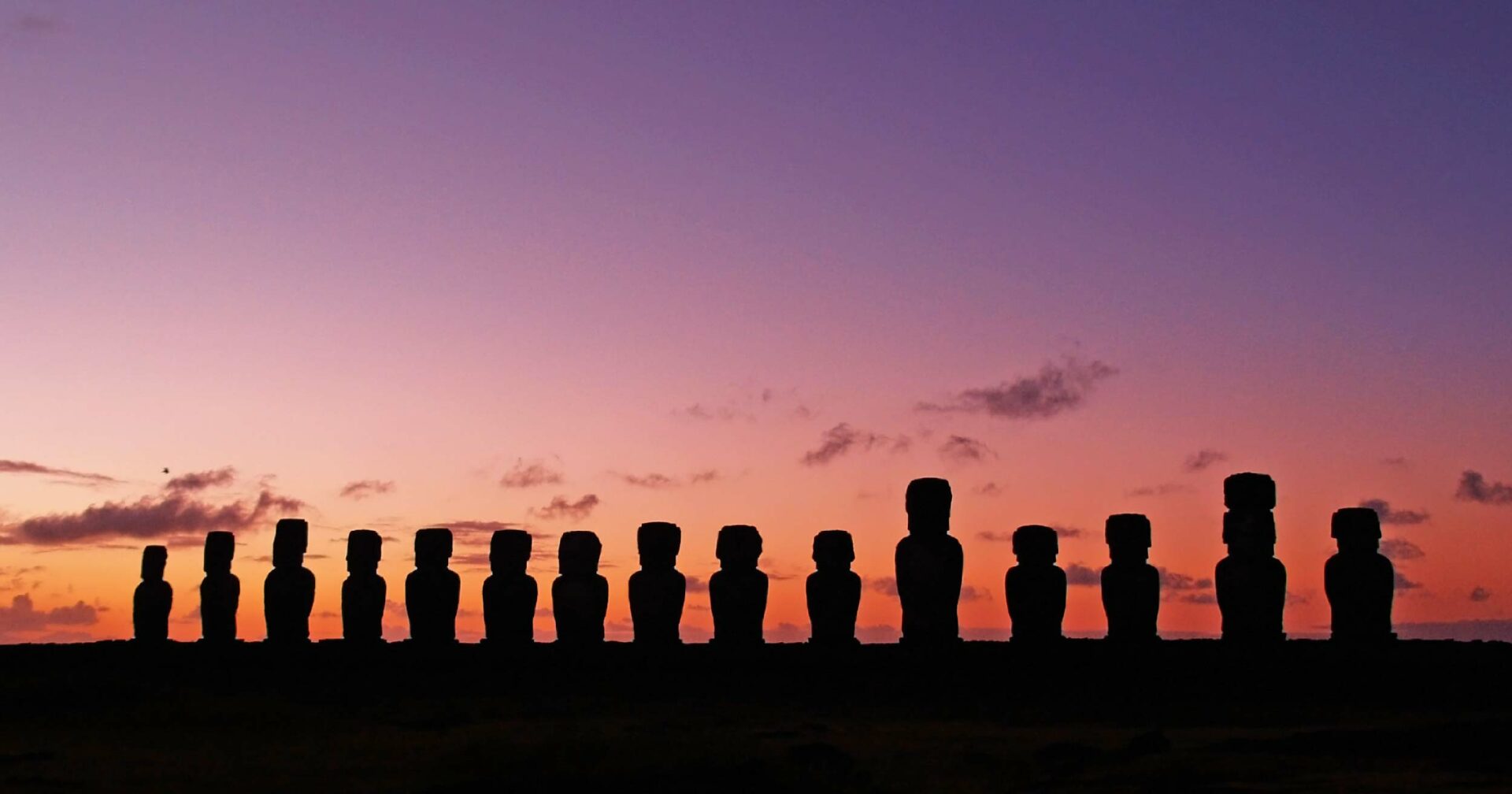 silhouette of moai statues in easter island with purple sky as the background