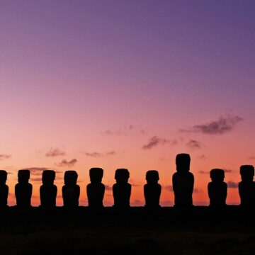 silhouette of moai statues in easter island with purple sky as the background