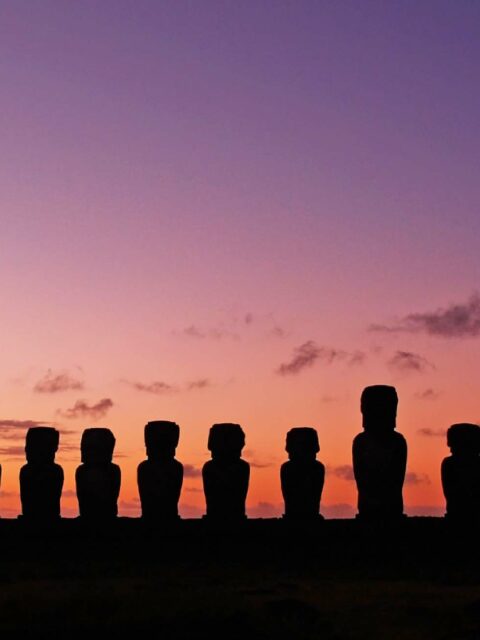 silhouette of moai statues in easter island with purple sky as the background