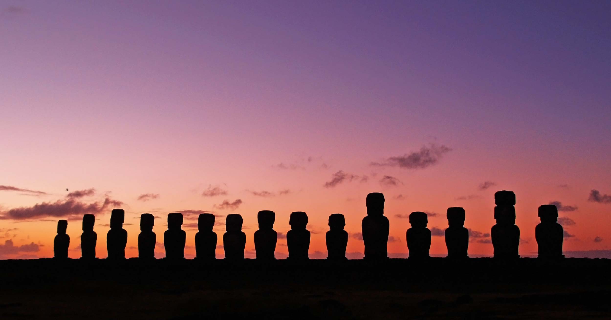 silhouette of moai statues in easter island with purple sky as the background