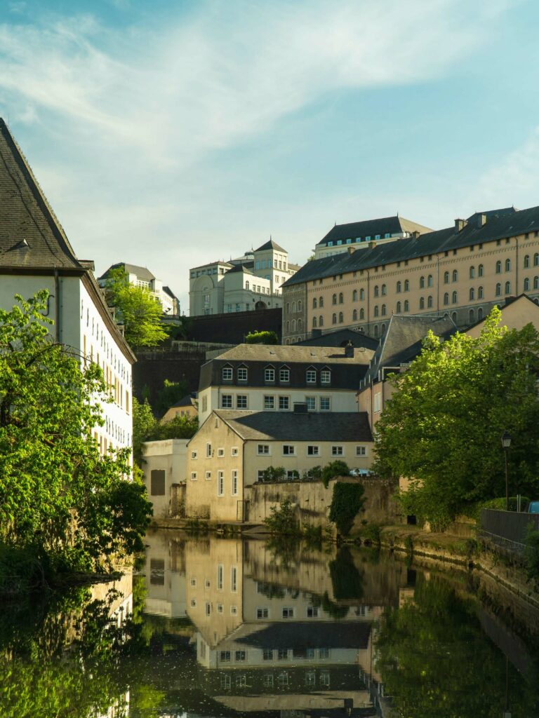 A river flowing through a modern city with brown and white concrete buildings lining the banks