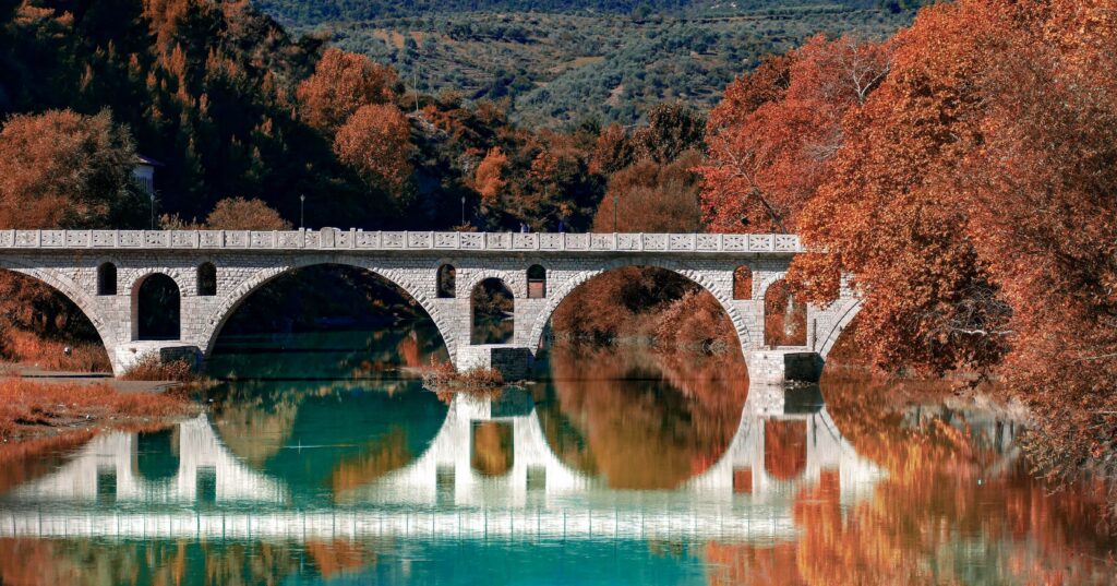 view of bridge creating a reflection in the water in albania